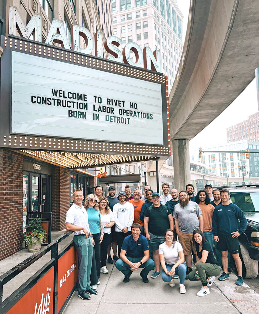 An image of the Rivet team under the Madison theater marquee in Downtown Detroit with marquee text that reads Welcome To RIVET HQ, Construction Labor Operations Born in Detroit